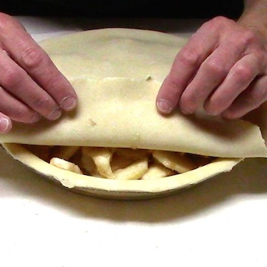 Putting dough top on pie